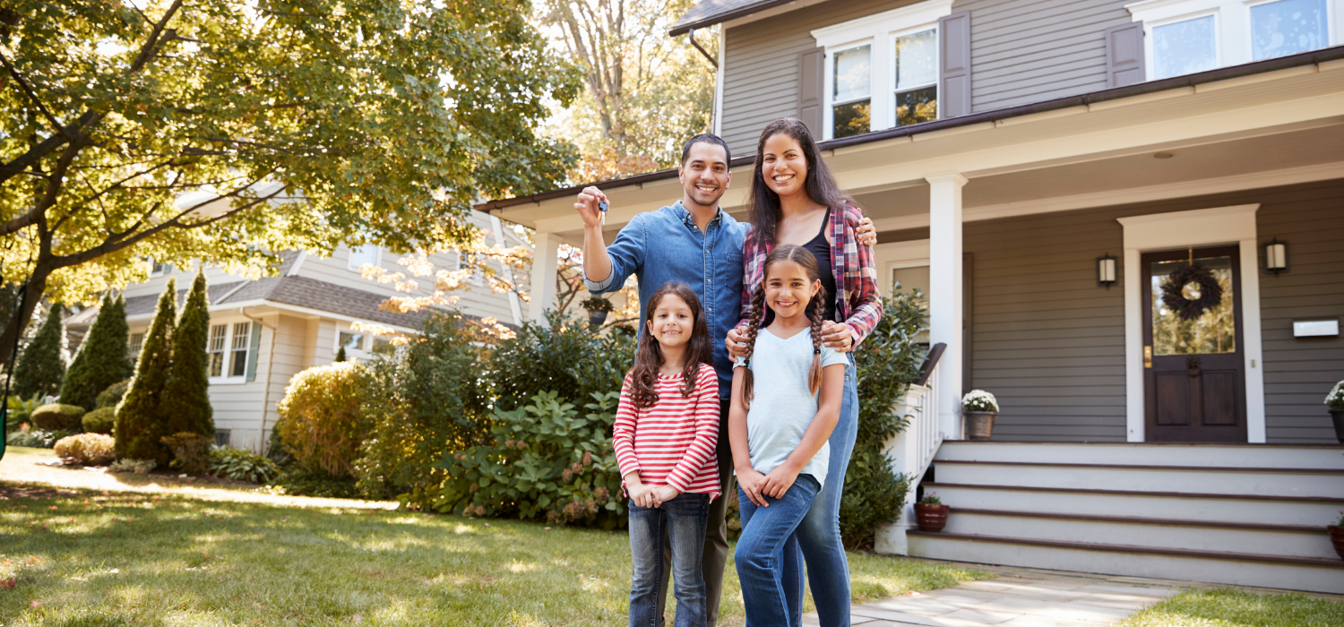 A family holding keys in front of their new home